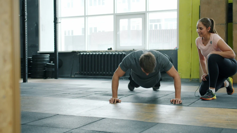 Private personal trainer coaching an adult client in a home gym