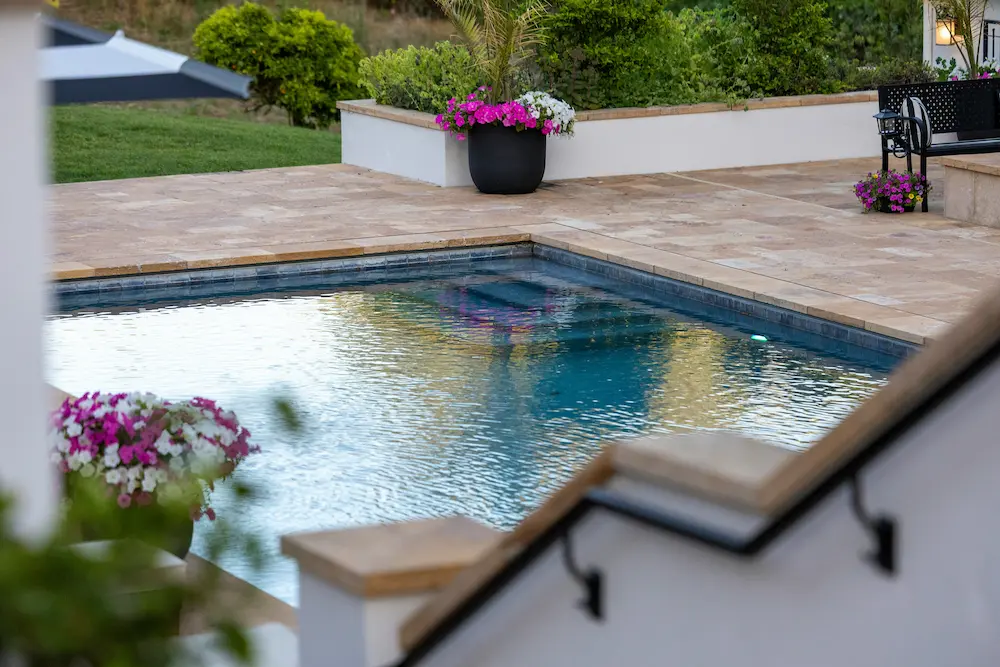 A calm, well-lit private home swimming pool with a graduated shallow end and clear water
